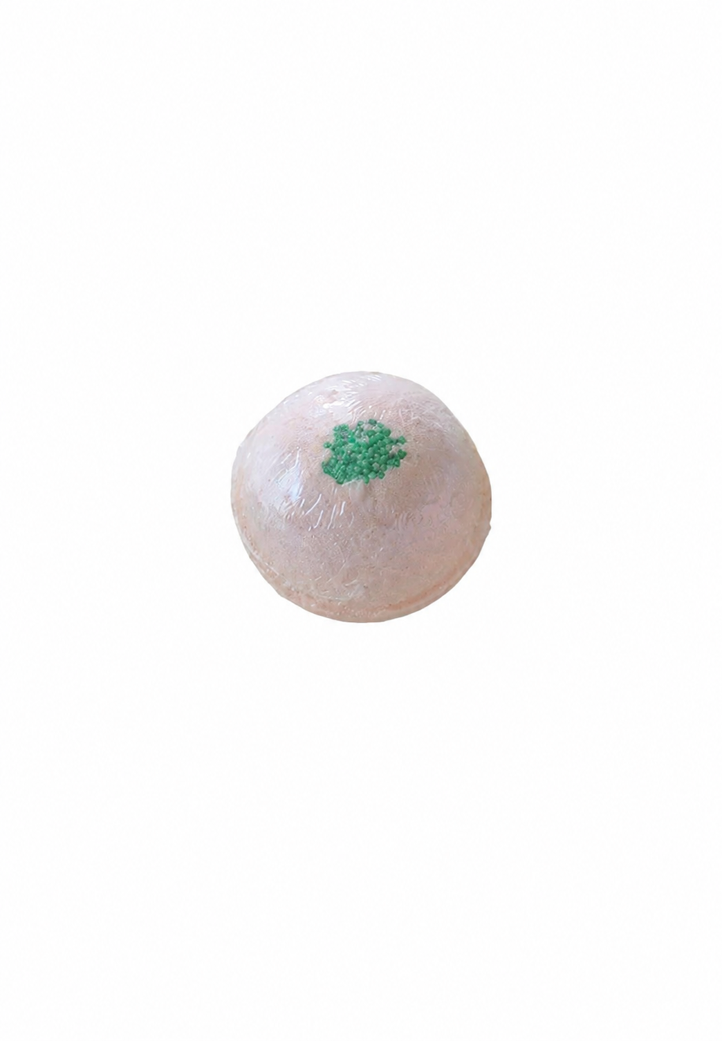 Boule de bain monoï effervescente rose pâle avec décoration verte sur fond blanc.
